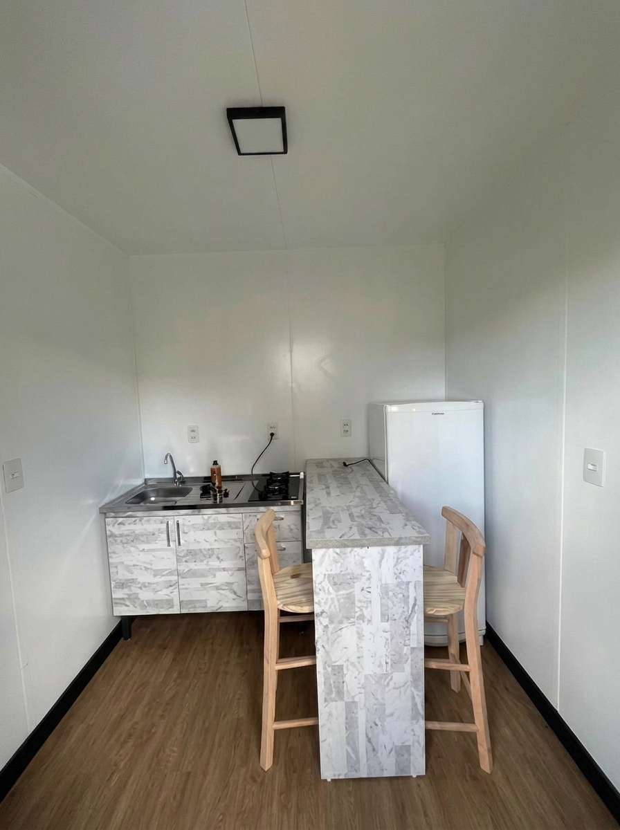 Cozinha com bancada, banquetas e geladeira